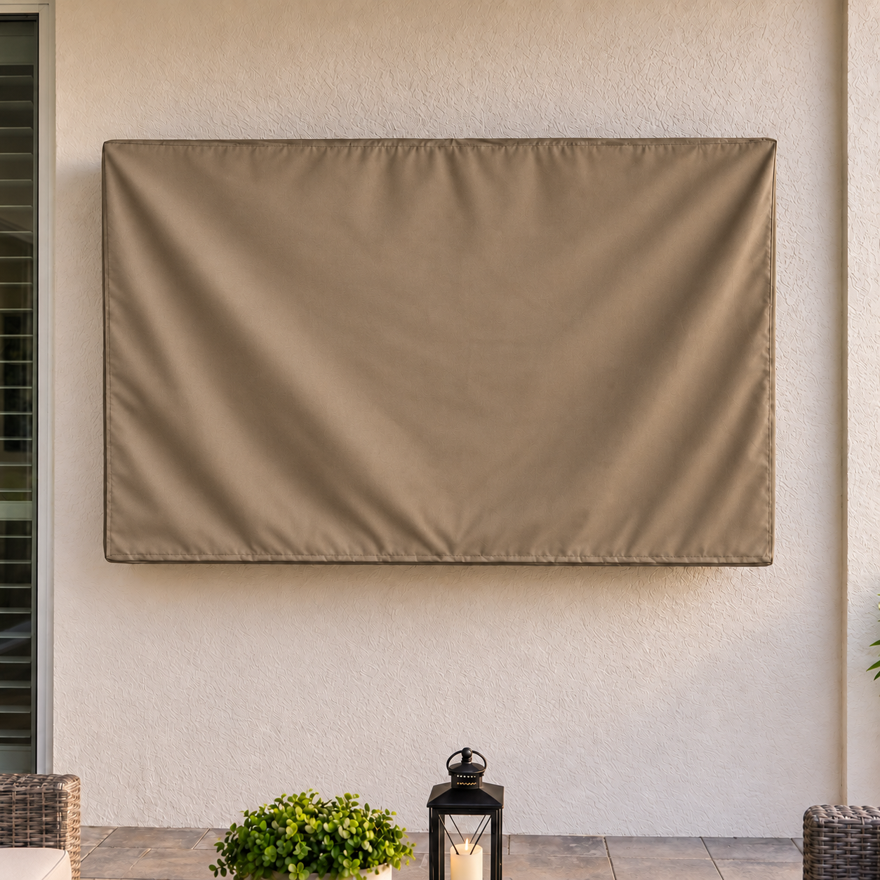 A rectangular patio cover in a warm taupe-brown color hangs on a stucco wall above a tiled patio floor, with a small potted plant and lantern below.