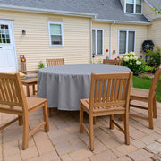 Round patio table covered with a gray Khomo Gear cover in a backyard with wooden chairs