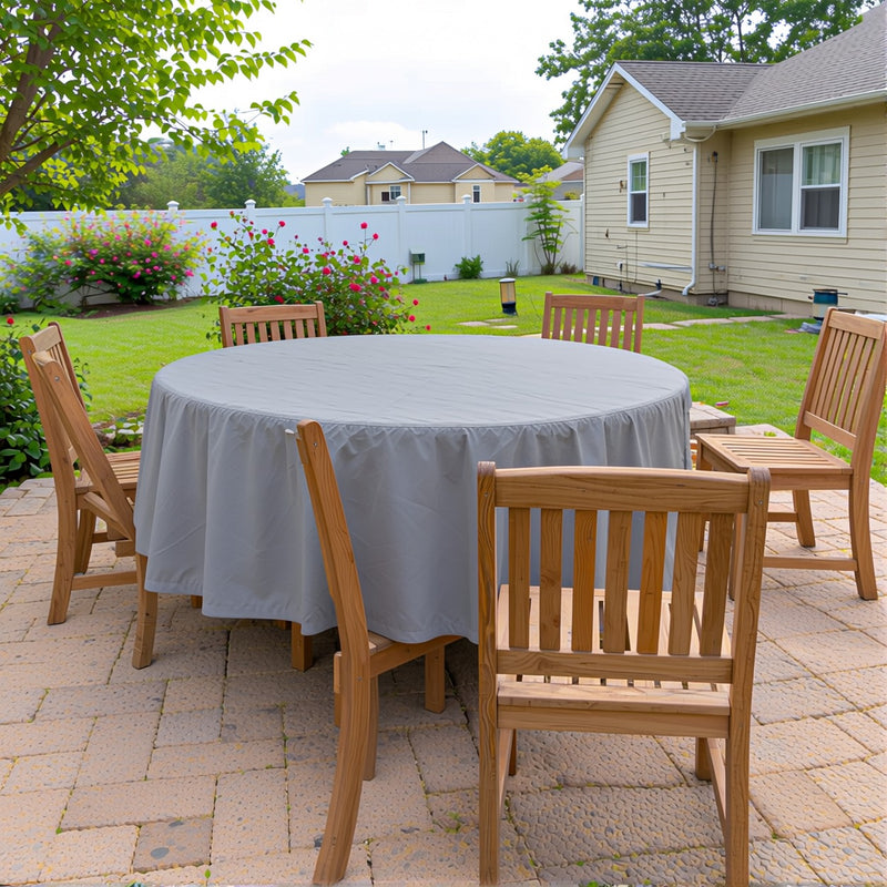 Gray Khomo Gear cover on a round patio dining table with chairs, backyard view