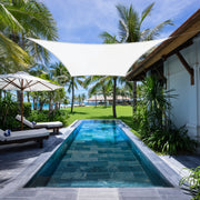 White Khomo Gear rectangle shade sail over a lap pool at a tropical resort