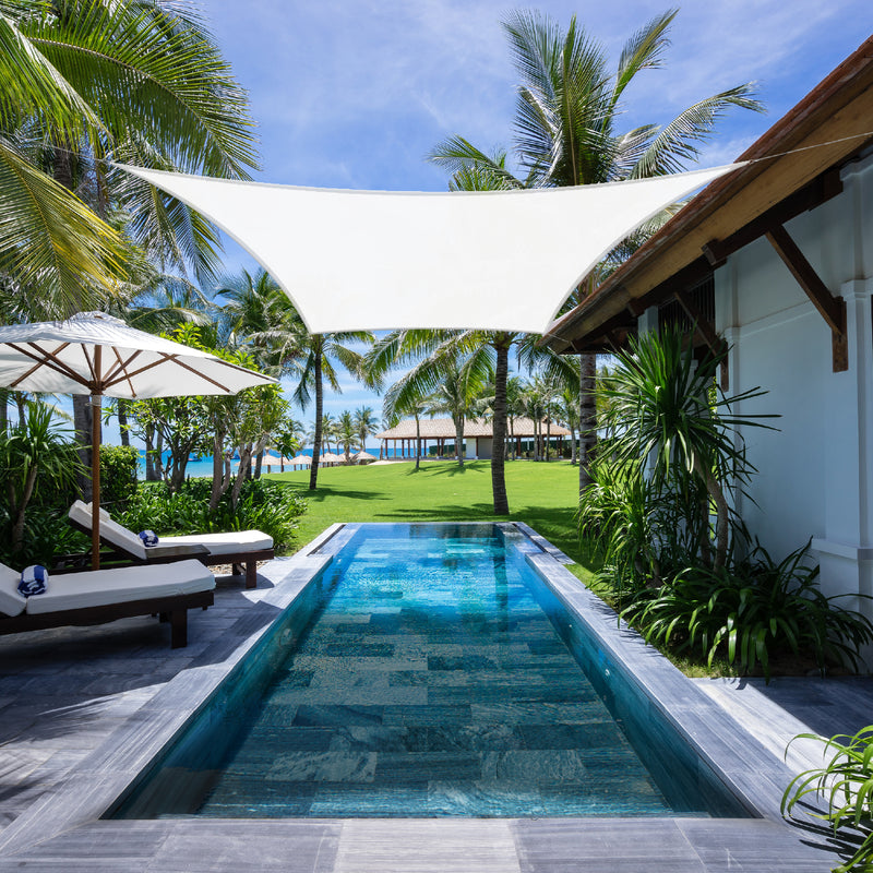 White Khomo Gear rectangle shade sail over a lap pool at a tropical resort